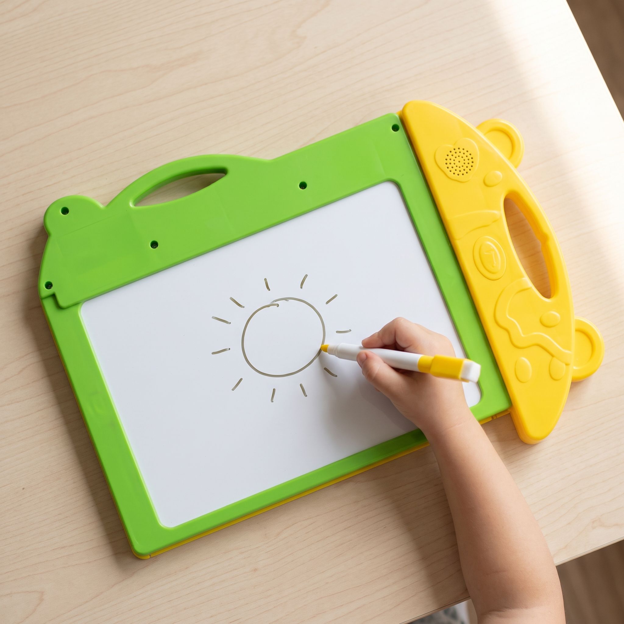 Mão de criança desenhando um sol na lousa do livro